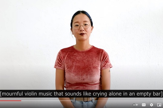 screenshot from You Tube showing a woman standing in front of a white background. The caption reads: mournful violin music that sounds like crying along in an empty bar.