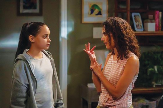 a still from a T V show with a woman talking to a teenager in sign language.