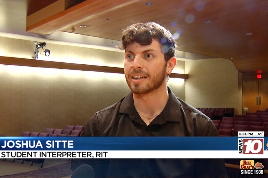 Joshua Sitte is shown in an auditorium standing for an interview.