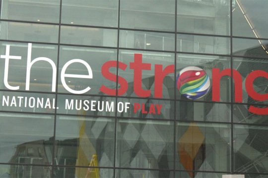 an exterior image of the stong museum which is all windows with their logo displayed in red and white.