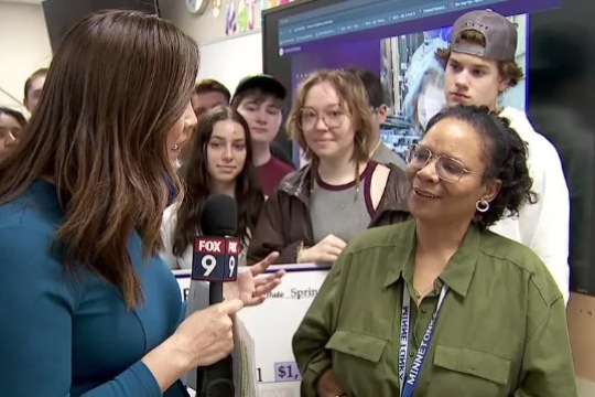 Tracy Ivy stands in front of students speaking to a news reporter.
