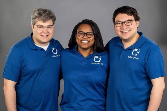 three people in blue polo shirts stand together for a photo.