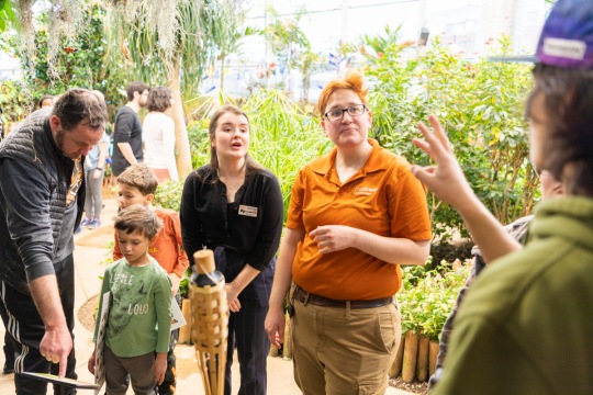 An interpreting student in a black top voices for a student asking a question to an employee of The Strong Museum. 