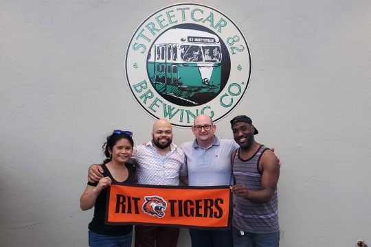 Four RIT/NTID alums, also the members of the NTIDAA Board of Directors, took a photo together with the banner to represent their Tigers pride. The Board members appeared in this picture include Christie Ong ’09, Ceasar Jones ’16, Jeremy Sebest ’99, and Omar Chung ’13. Photo credit: Ceasar Jones