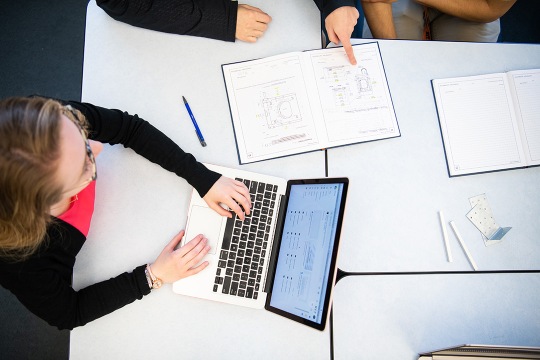 Overhead photo of white woman typing on a laptop.