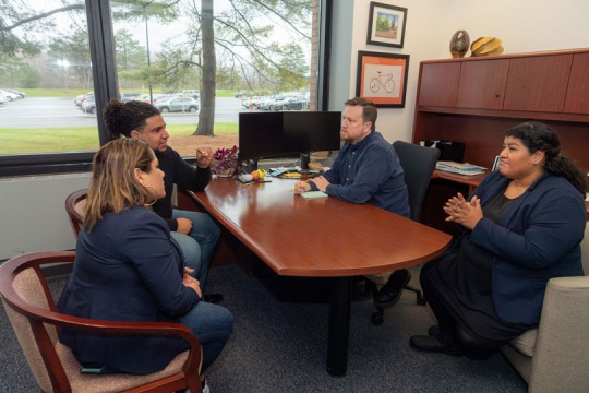 Female ASL interpreter and male individual sit across a table from a male student and his mother.