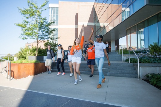 Students on campus high-five each other.