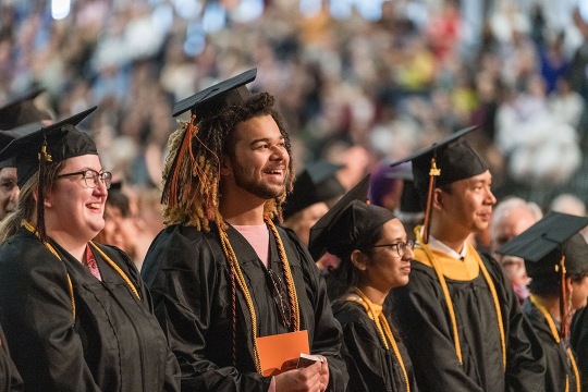 Graduates smiling in cap and gown.