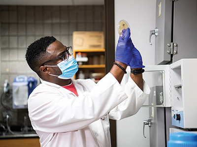 Student researcher holding up petri dish