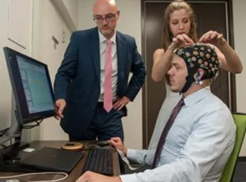 Clinicians and person with electrode cap on head.