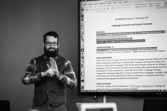 professor using sign language in front of a text presentation.