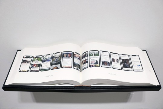 open book with screenshots of news stories from a smartphone.