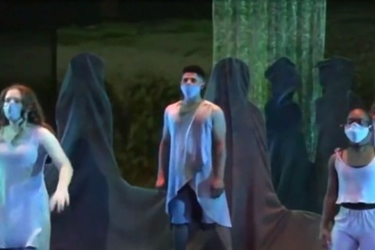 three performers on a stage dressed like spirits.