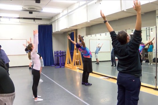 instructor and students in a dance studio.