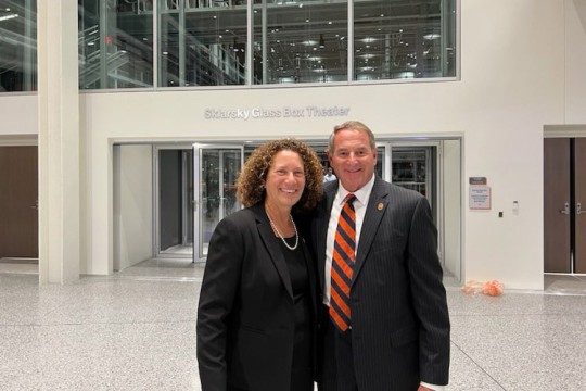 a couple stand in a lobby area outside of the Sklarsky Glass Box Theater.