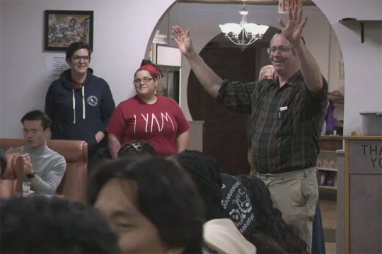 man standing with his arms in the air in a crowded resaurant.