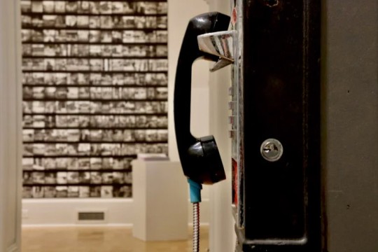 a sideview of a payphone in a museum like room.