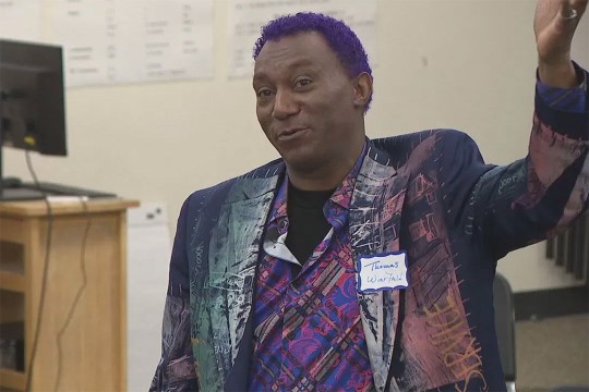 a closeup of Thomas Warfield wearing a purple patterned blazer speaking to students