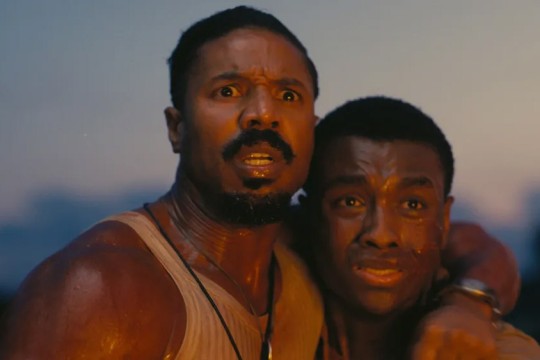 Two men, covered in sweat, stare ahead with intense expressions at sunset.