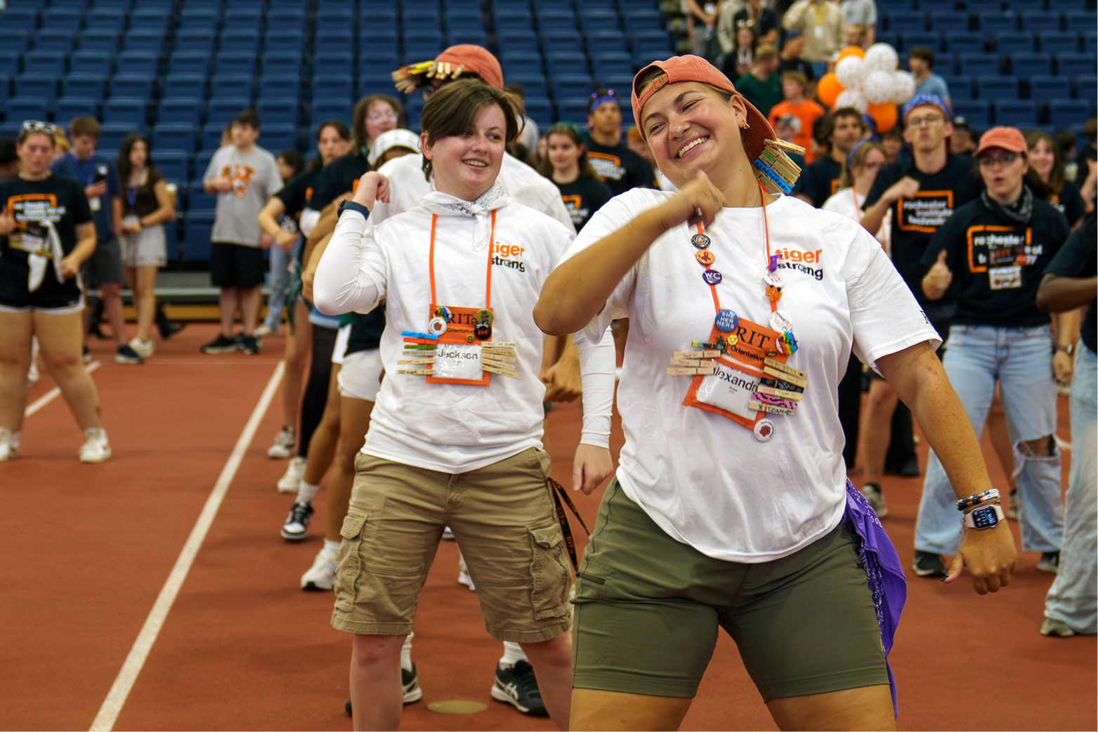 Student orientation leaders wearing “Tiger Strong” shirts lead a group dance or movement activity inside a large indoor arena, surrounded by incoming students.