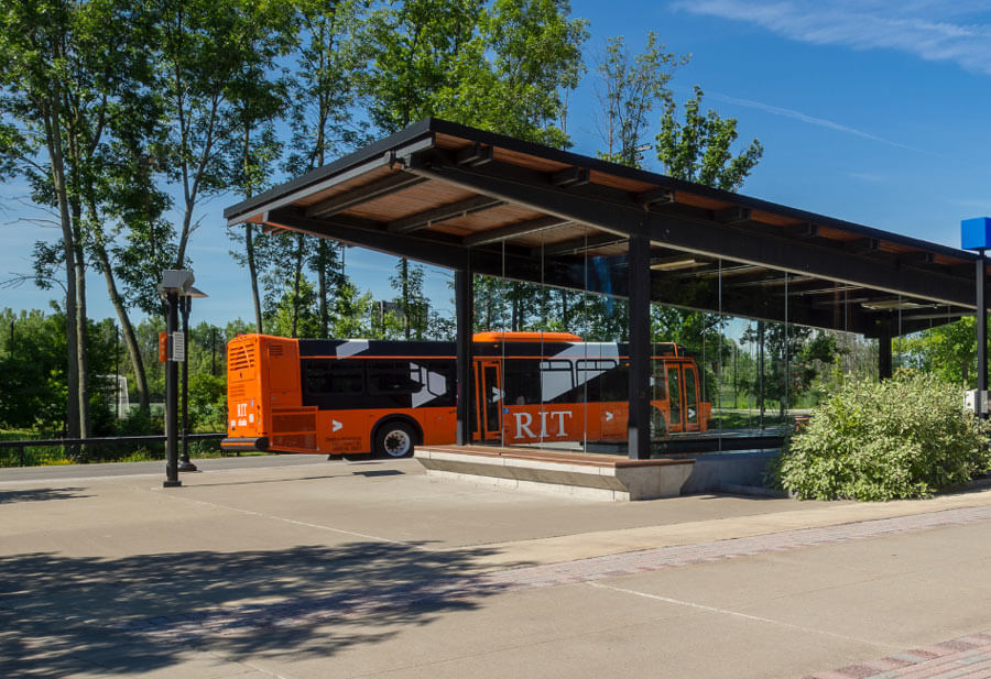 An RIT shuttle parked at a campus shuttle stop.