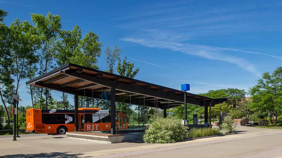 An R I T bus pulling up to a bus stop on campus.