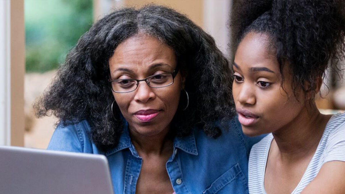 A mother and daughter looking at a laptop screen together.