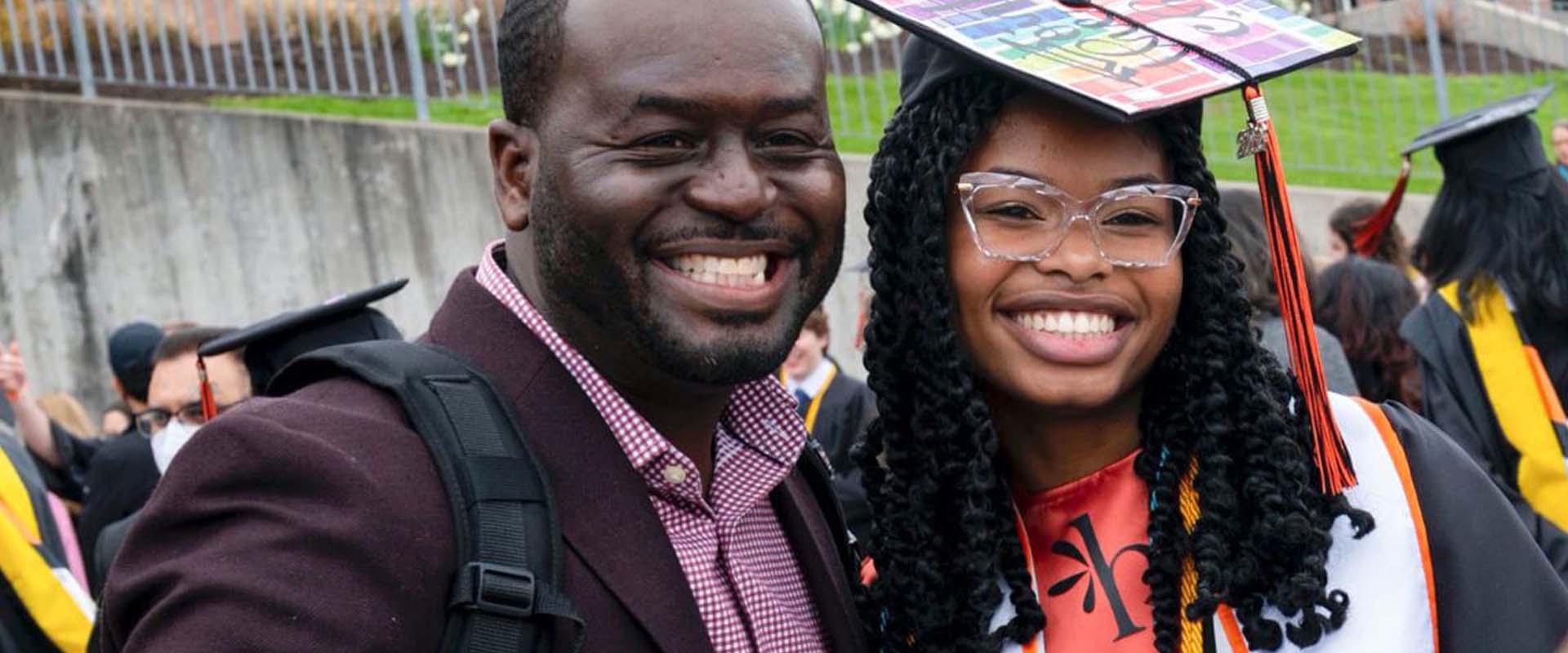 A parent posing with their graduating student during Commencement celebrations.