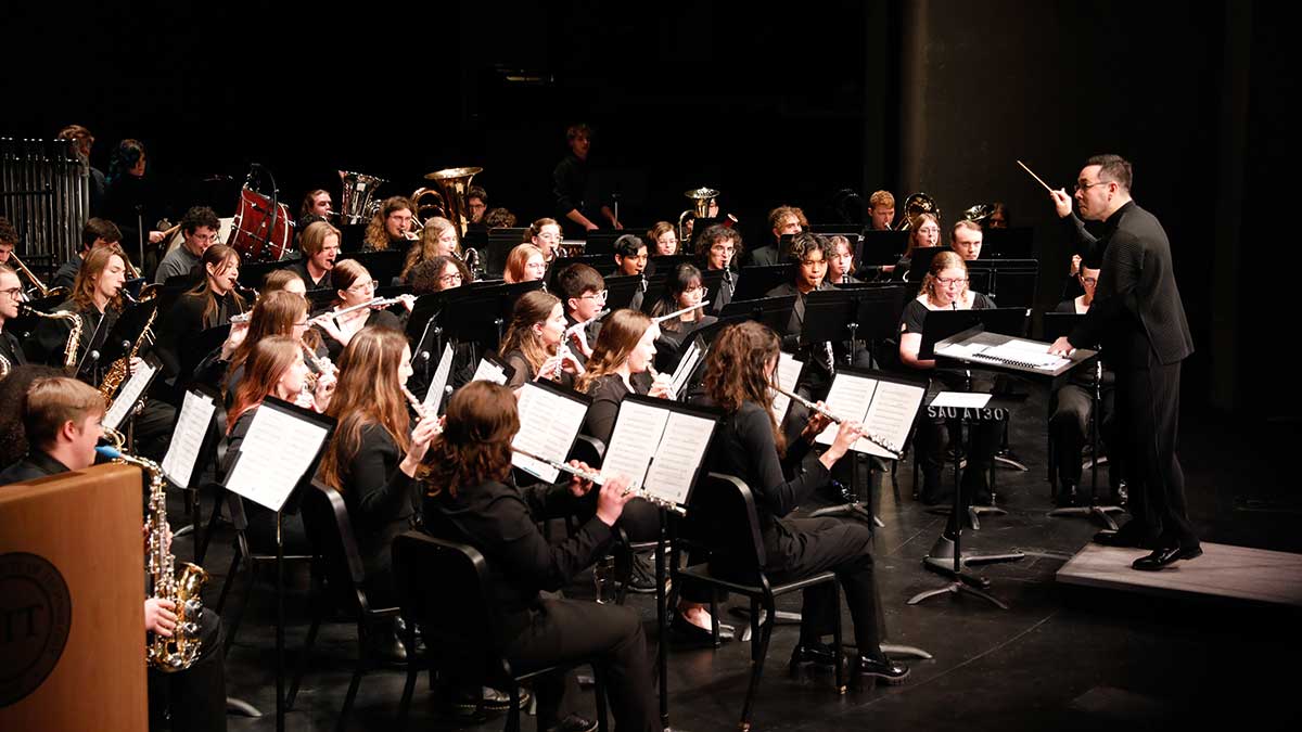 A music director conducting a piece of music played by the RIT Concert Band