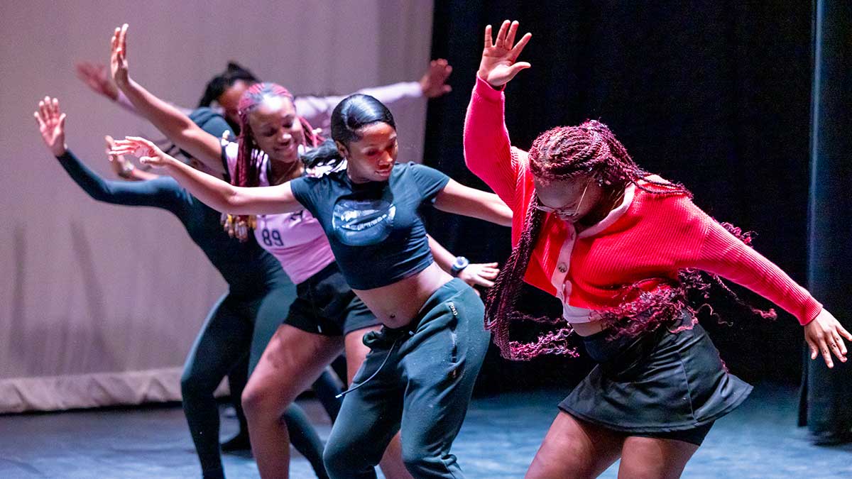 five people in a line dancing in hip-hop style.