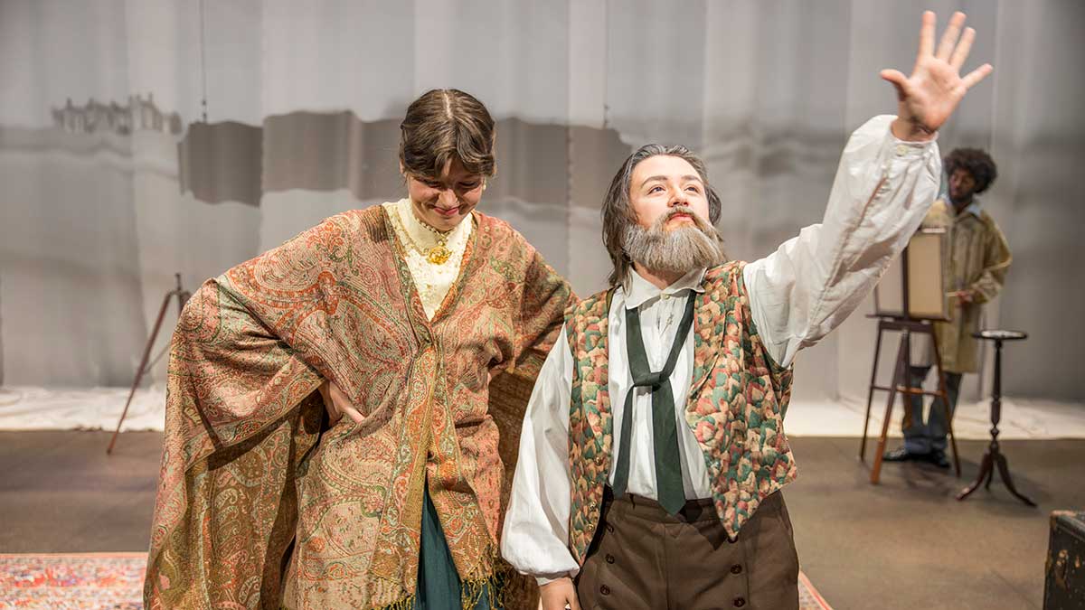 two students in costume performing on stage.