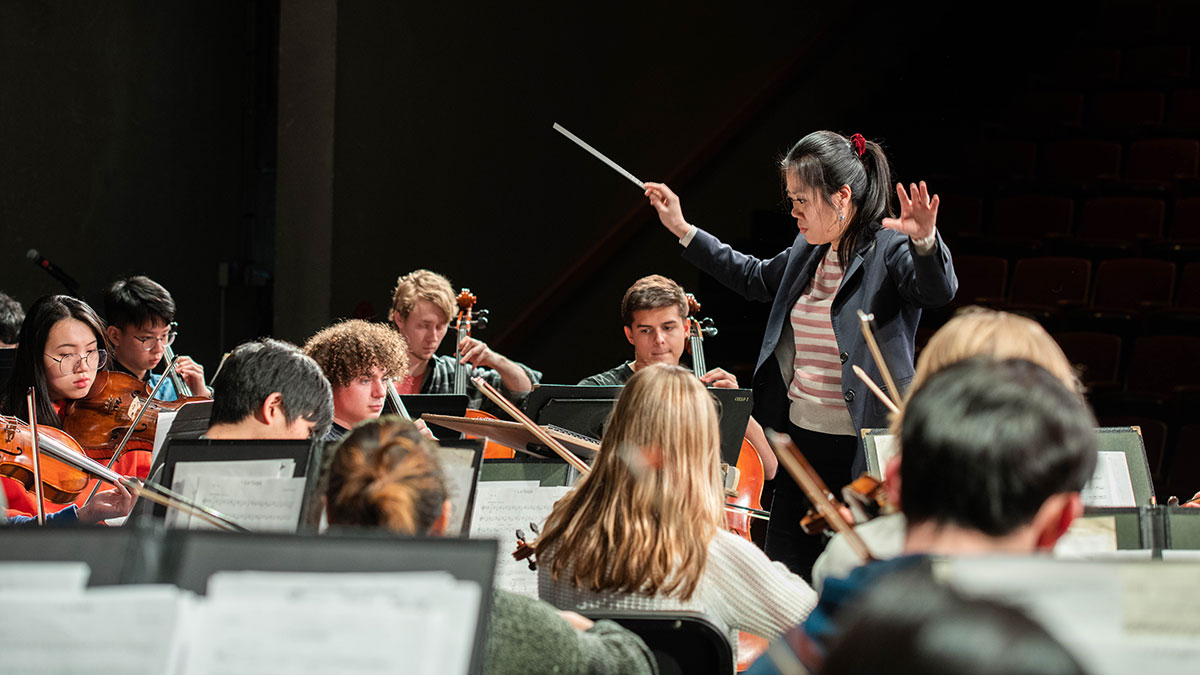a person conducting a strings ensemble.