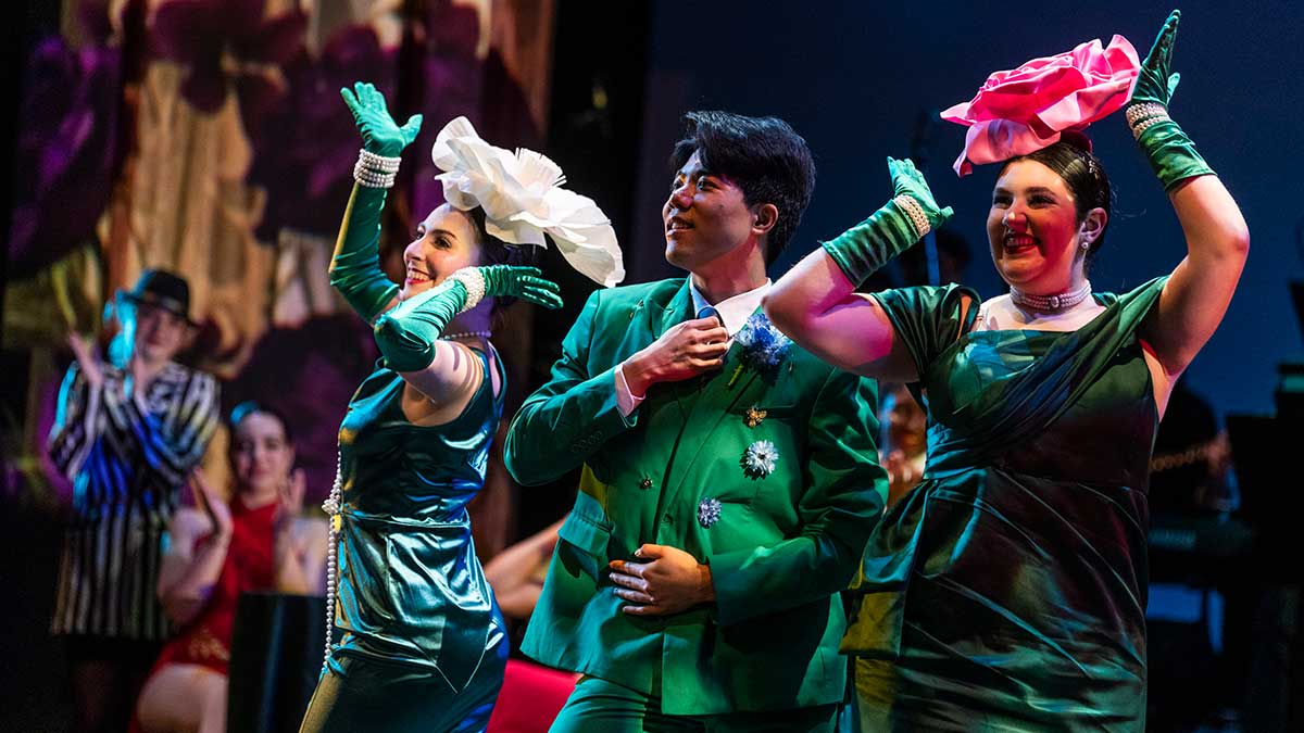 actors in emerald green costumes perform on stage.