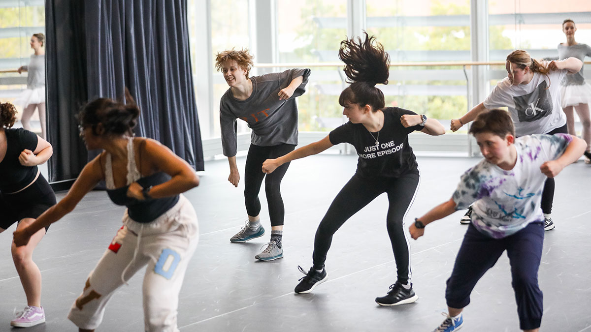 students practicing a dance in a studio.
