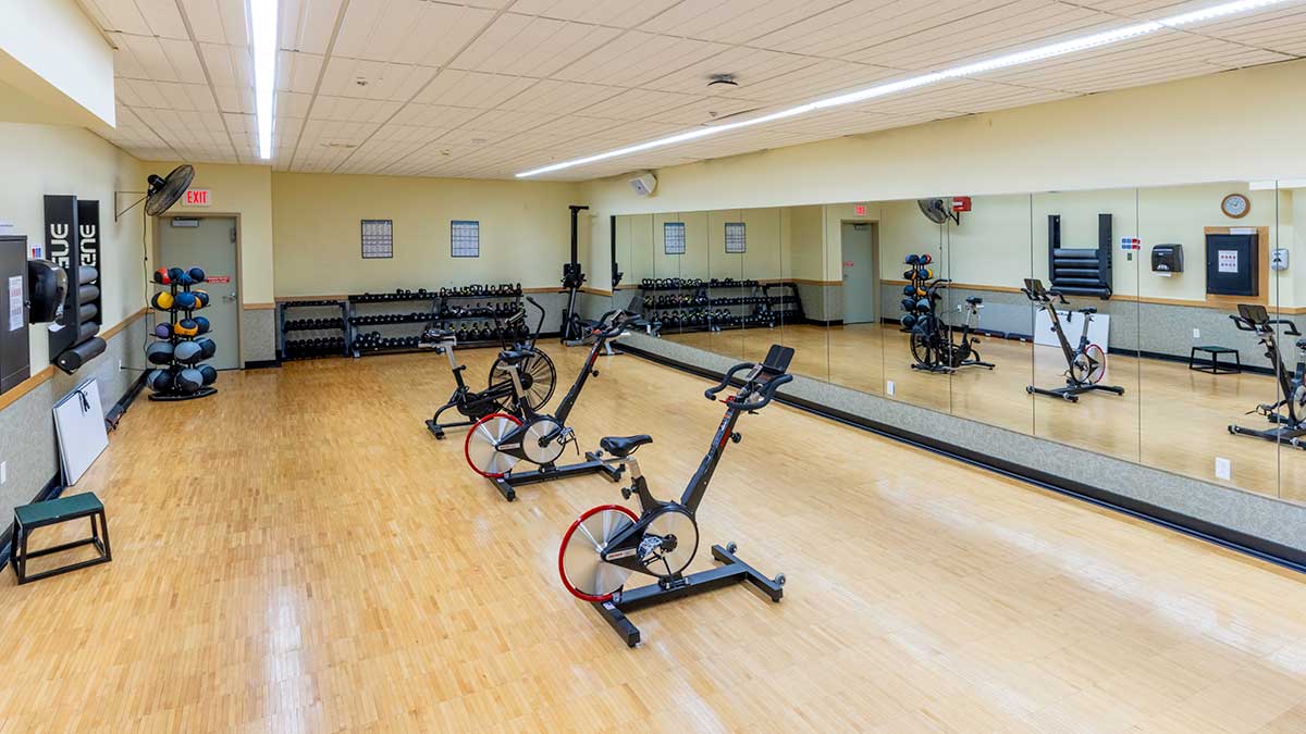 a large exercise space with mirrored wall and spinning machines.