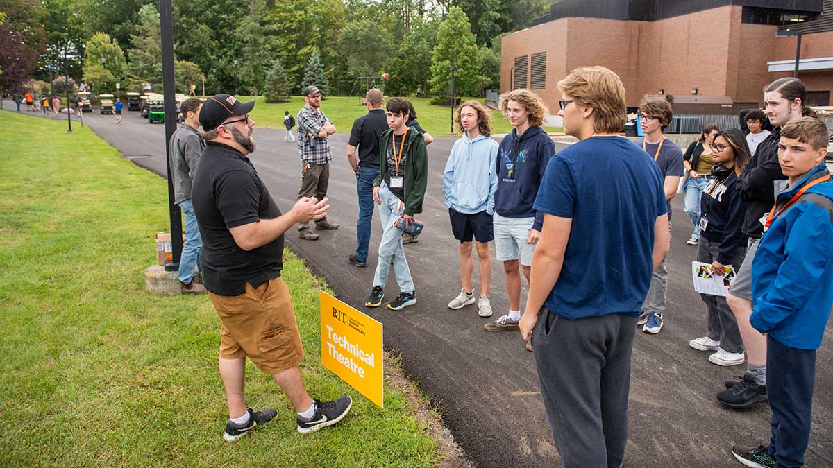 students gathered outside near a sign that says, technical theater.