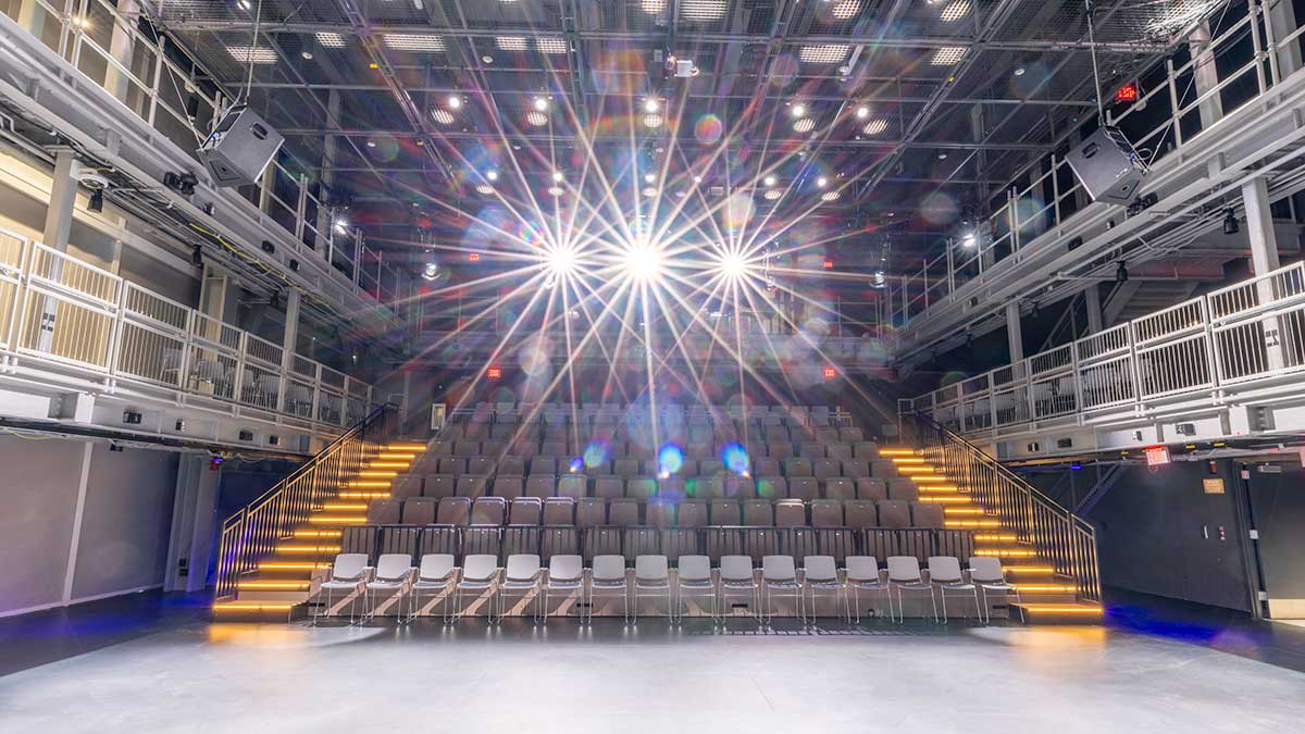 view of stadium seats in a performance space, with the overhead spotlights shining into the camera.