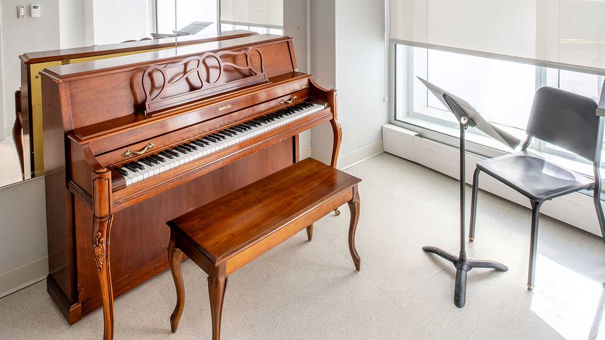a room with a piano, chair, and music stand.
