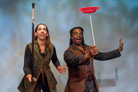 Two people balancing objects on stage 