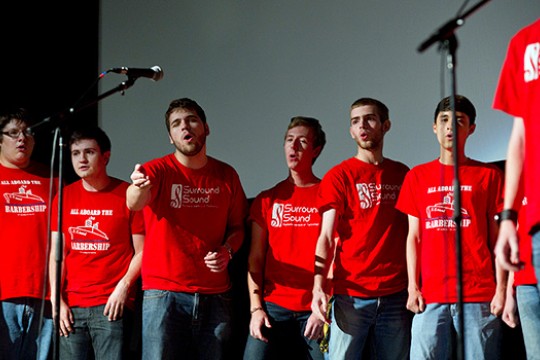 seven college students wearing red T shirts singing a cappella.