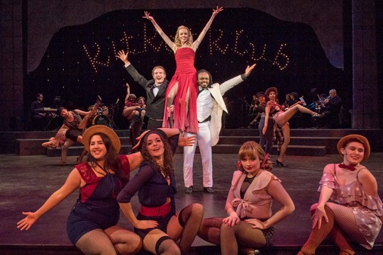 actors dressed in 1930s cabaret attire pose on stage