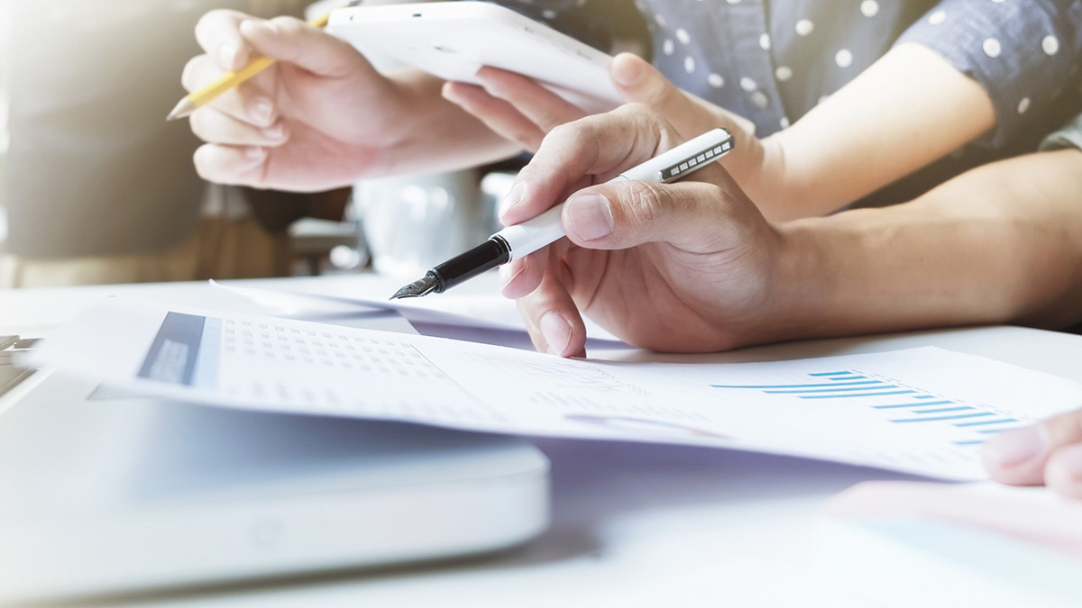close-up of hands holding papers and making notes.