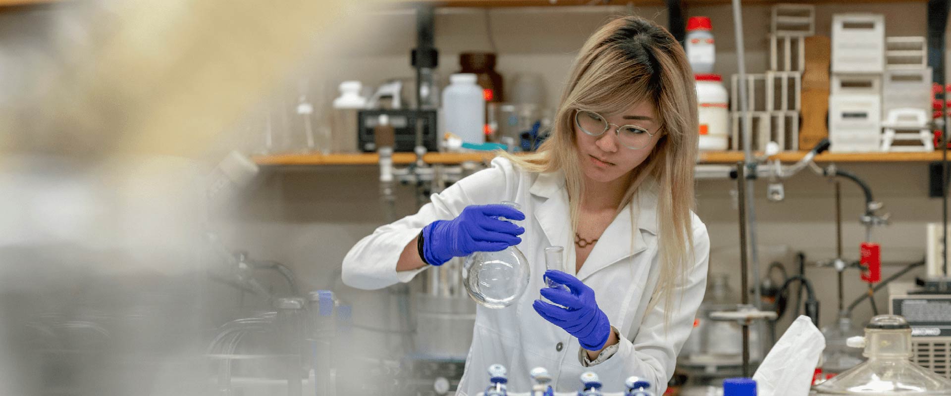 student researcher in a lab setting working with test tubes.