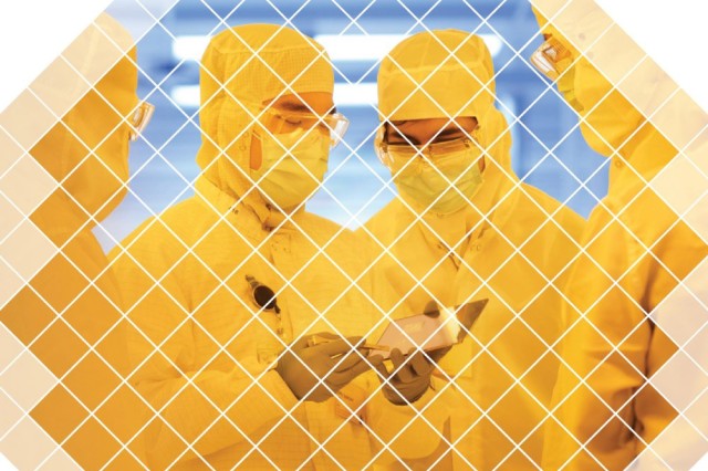 four people in yellow clean suits looking at microchips.