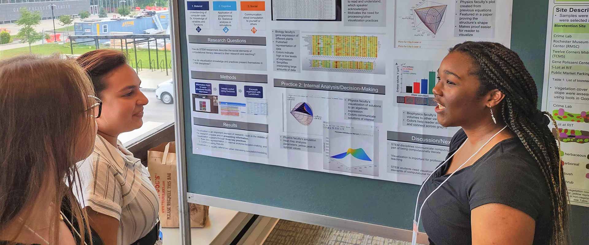 a student giving a poster presentation to two other students.