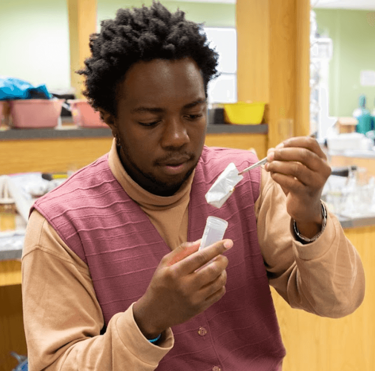 Evan Batte holding a sample with tweezers over a container.