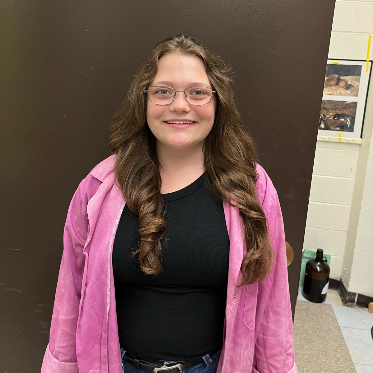 Isabelle standing in front of a wall wearing a pink sweater.