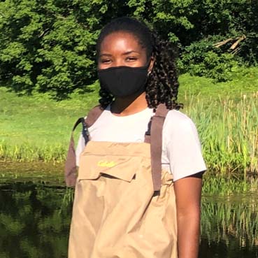 Mercy standing in a pond in waders. 