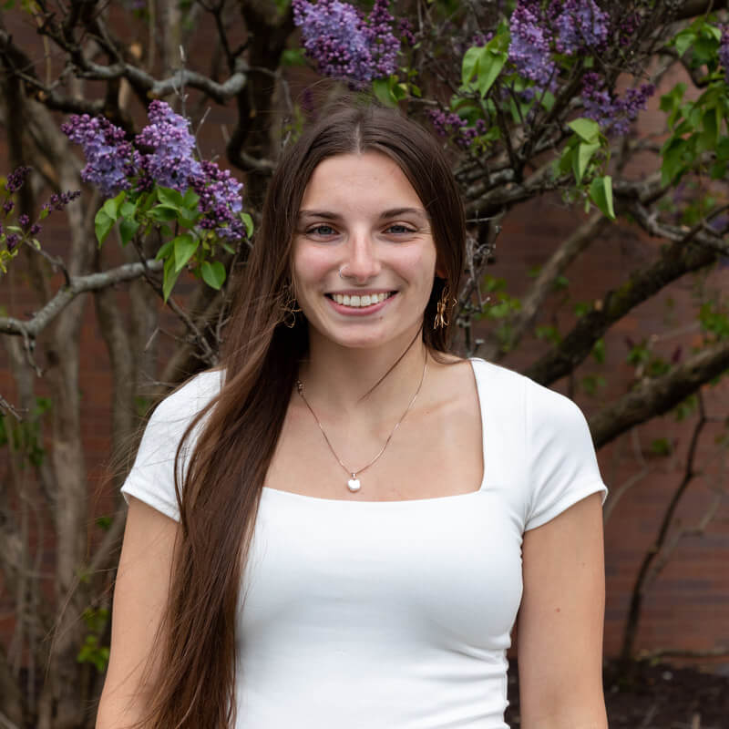 Paige Arieno standing in front of a tree with purple flowers