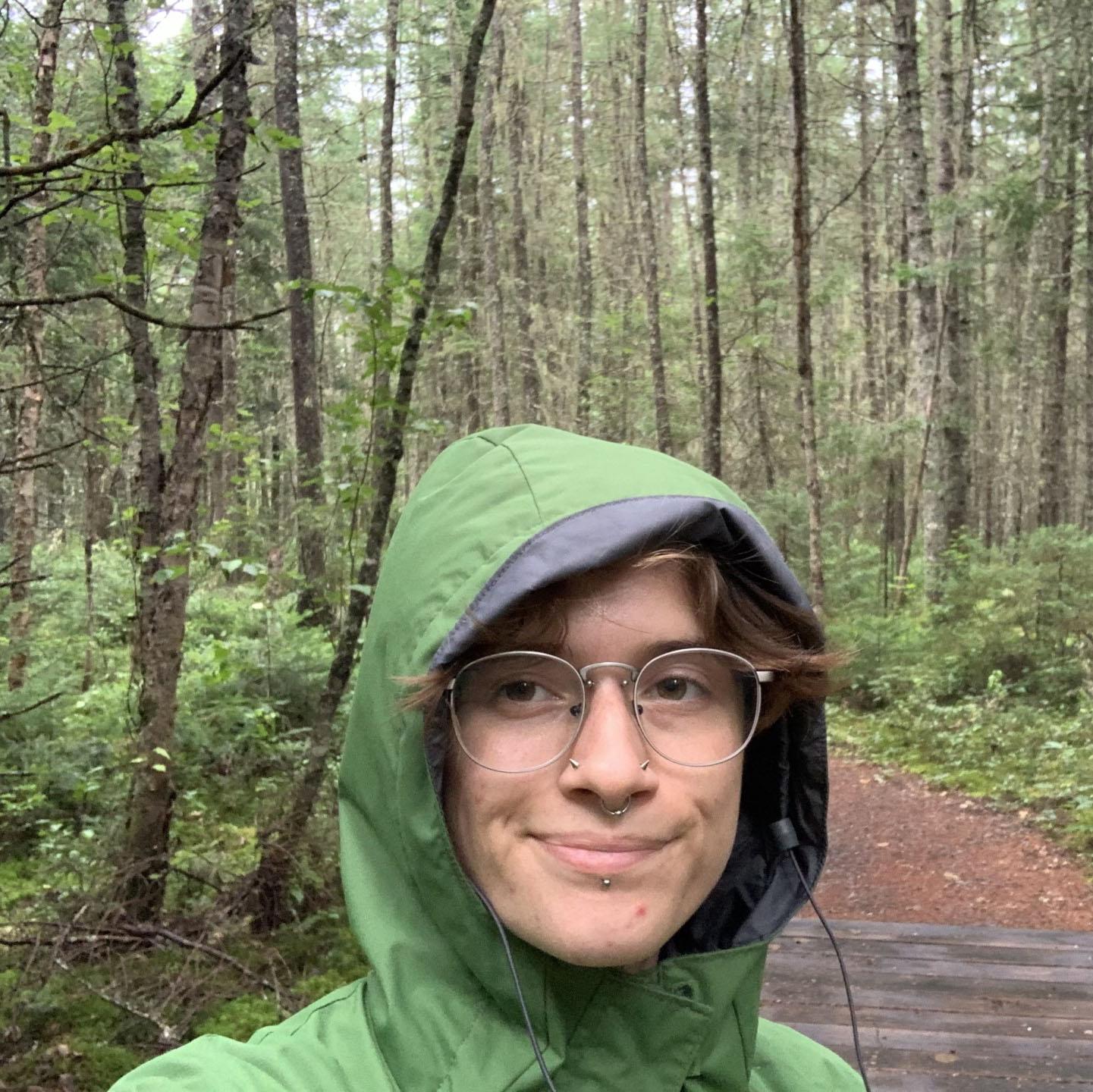 Ren, wearing a rain jacket, in a forest.